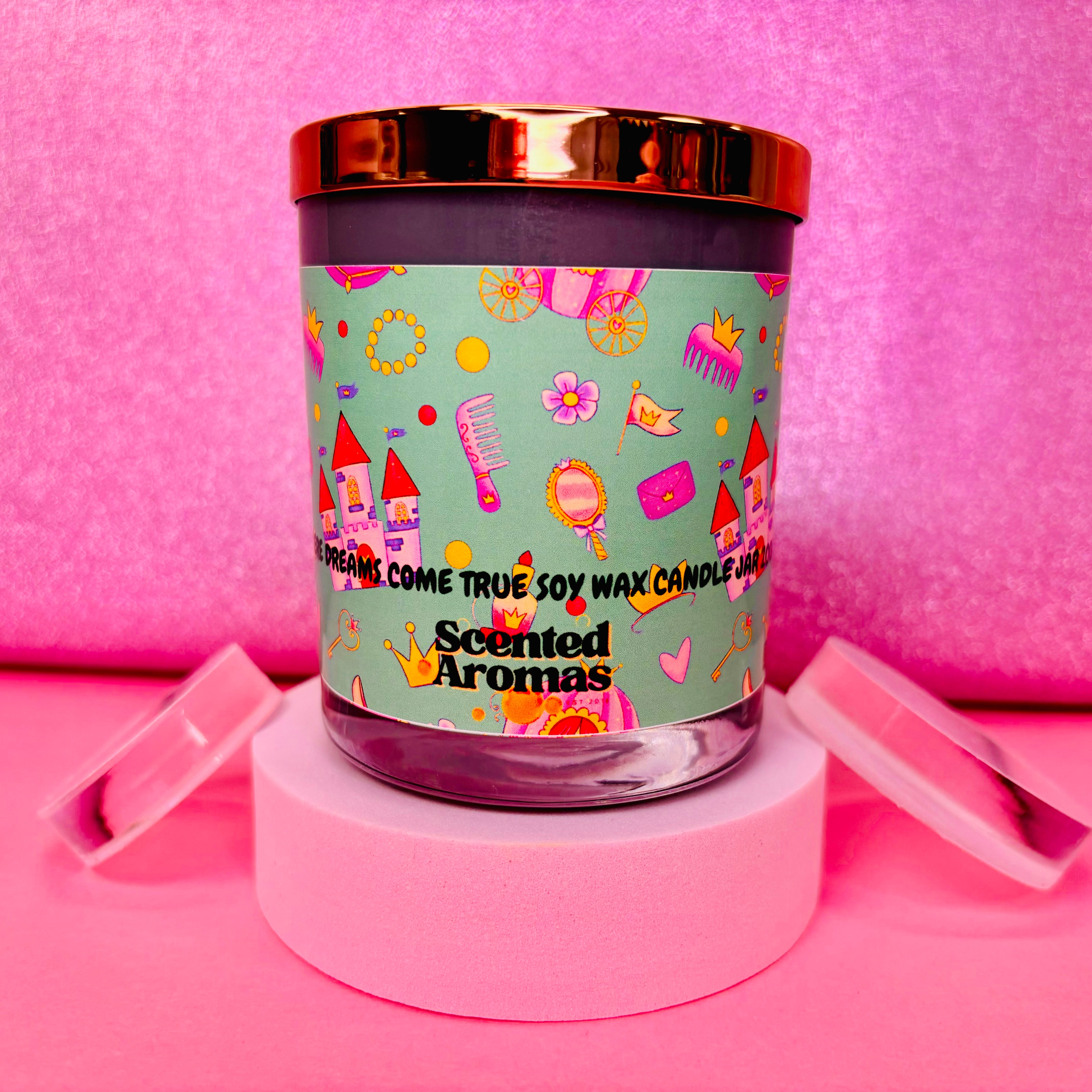 A vibrant Dreams Come True Candle - 200g by The Soap Gal x, featuring a playful design on a pink background, beautifully set on a white round base.