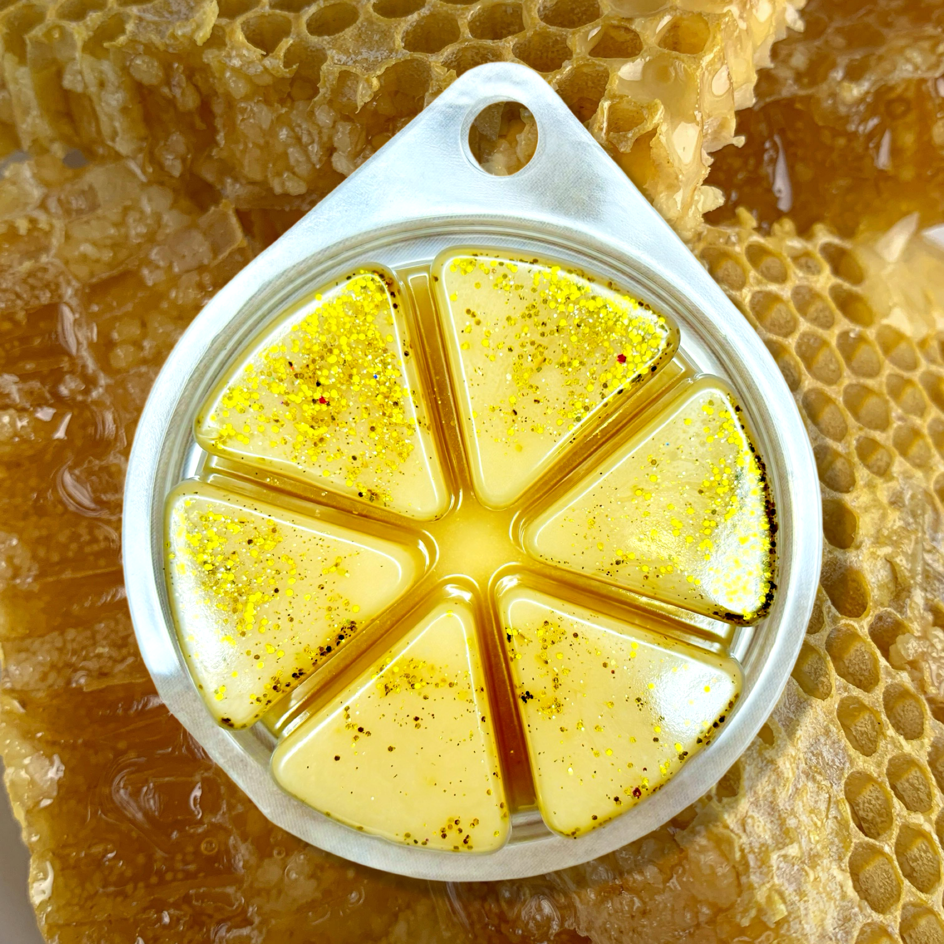 An 85g circular metal mold featuring The Soap Gal x's Almond Milk and Honey Wax Melts with honeycomb-shaped triangular sections, set against a natural honeycomb backdrop.