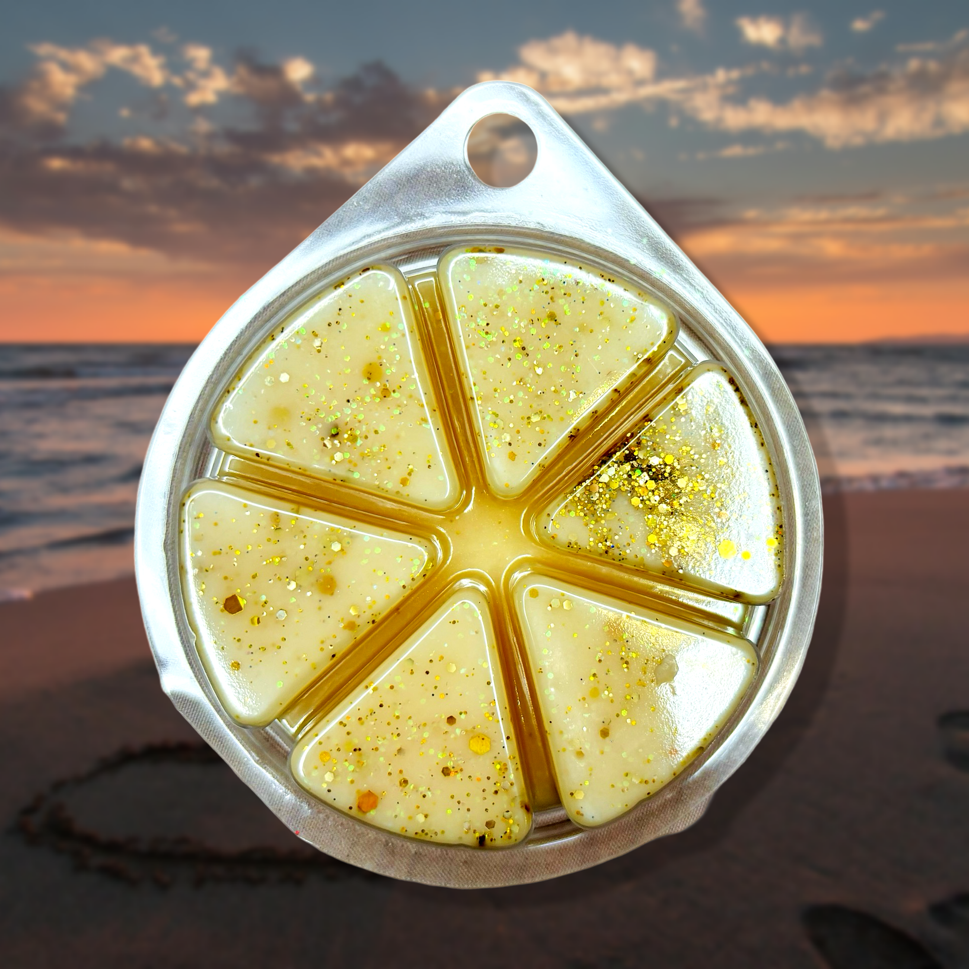 The Soap Gals' Brazilian Bum Cream Wax Melt 85g features yellow, glittery wax in a round container with six triangular compartments, evoking the essence of a beach sunset.