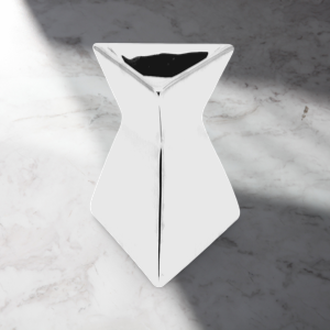 The Soap Gal x's Silver Chrome Triangle Wax Warmer sits elegantly on a marble surface, with light casting a diagonal shadow, adding sophistication to any room.