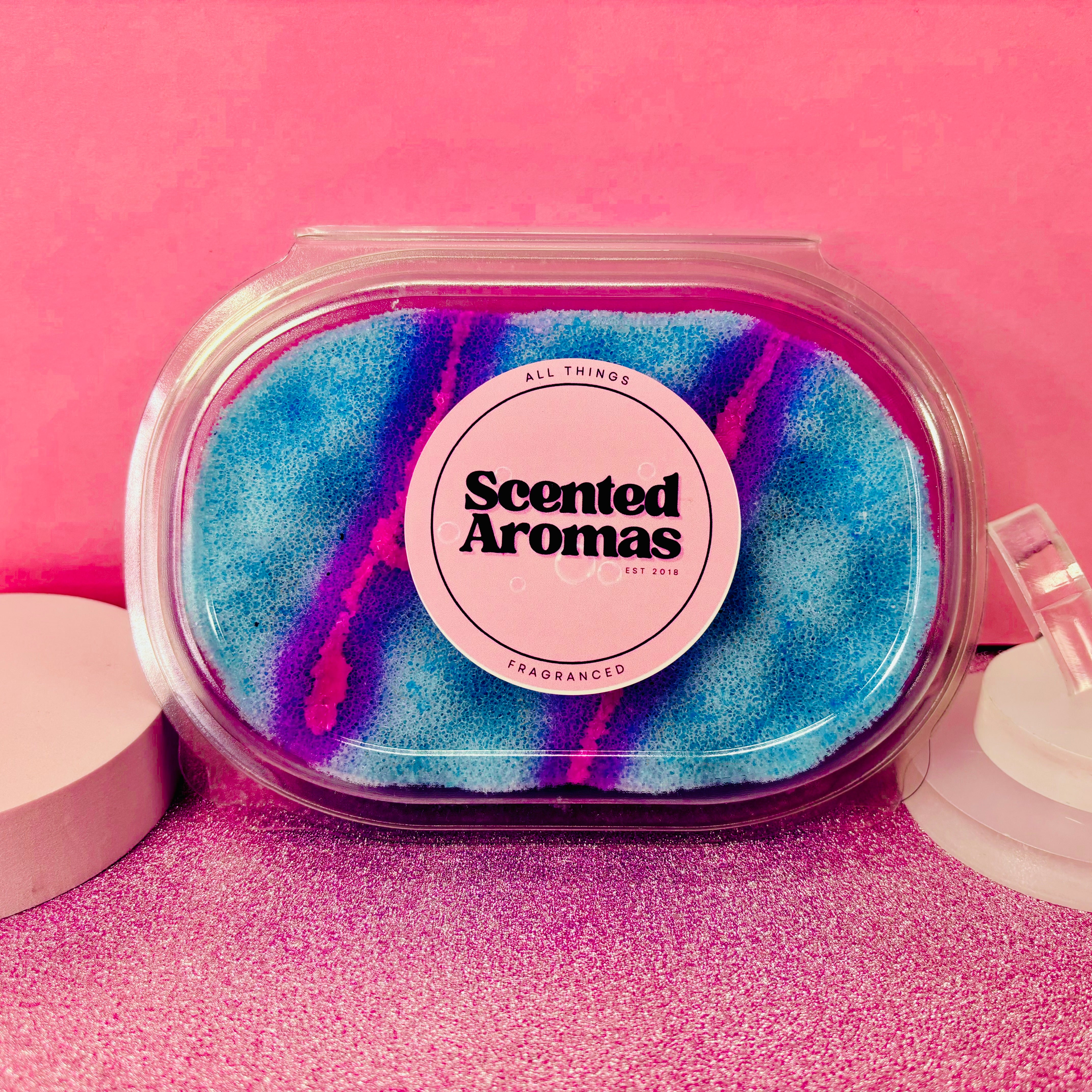 A package of "Bubblegum Exfoliating Soap Sponge" from The Soap Gal x features a blue and purple design, set against a pink background, promising long-lasting freshness.