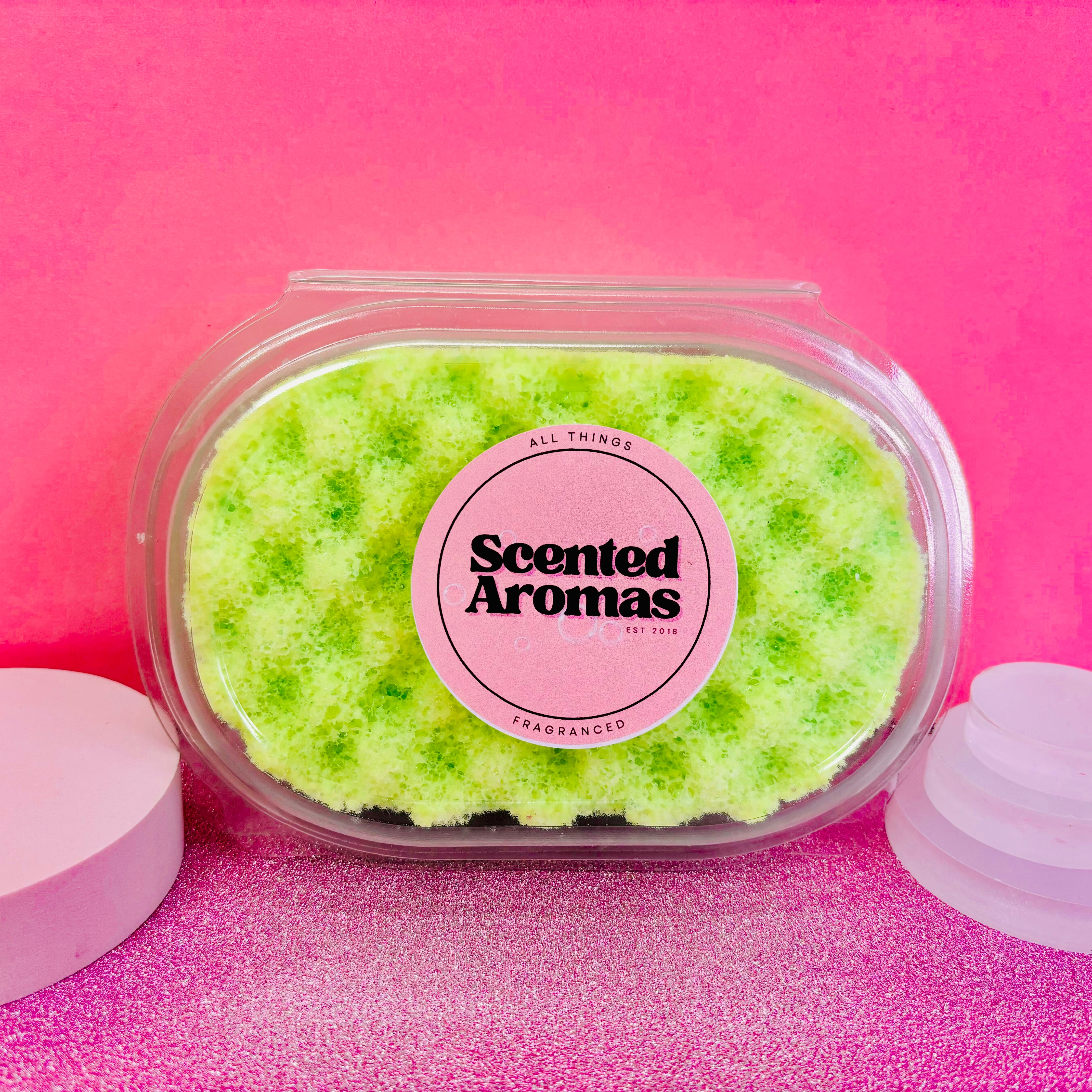 A Strawberry and Lime Exfoliating Soap Sponge by The Soap Gal x is displayed in a clear plastic container against a pink background, perfect for adding a refreshing touch to your skincare routine.