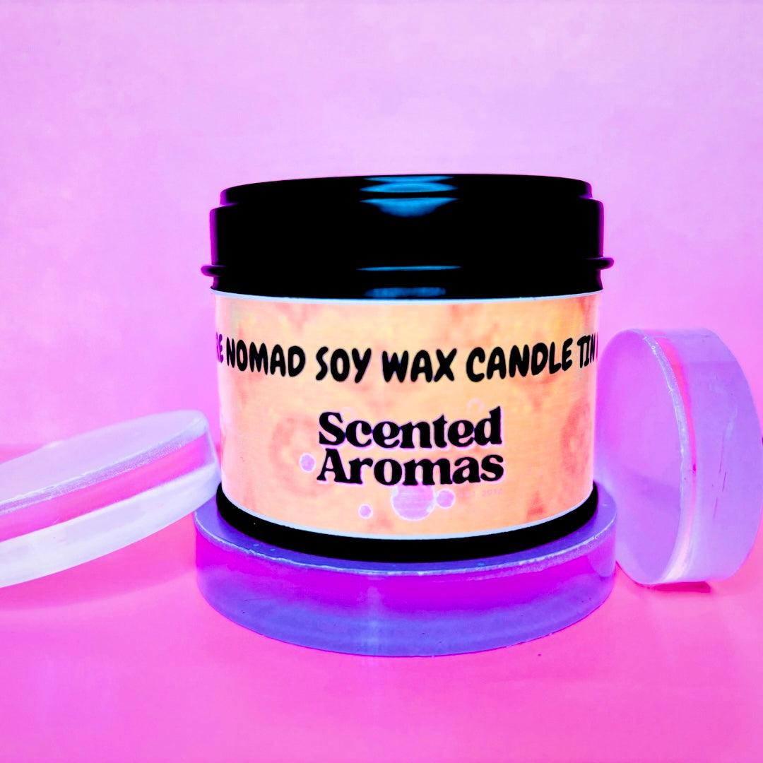 An Ombre Nomade Candle Tin - 100ml from The Soap Gal x, infused with a luxury unisex woody fragrance, is placed on a pink surface with the lid removed and leaning nearby.