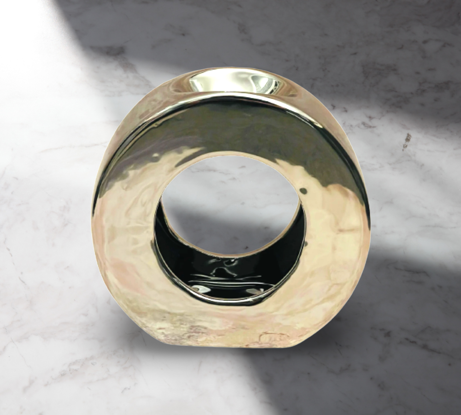 A Silver Ceramic Circle Wax Melt Warmer by The Soap Gal x, featuring a shiny, circular design with a hollow center and reflective surface, sits against a marble background, seamlessly integrating into stylish home decor.