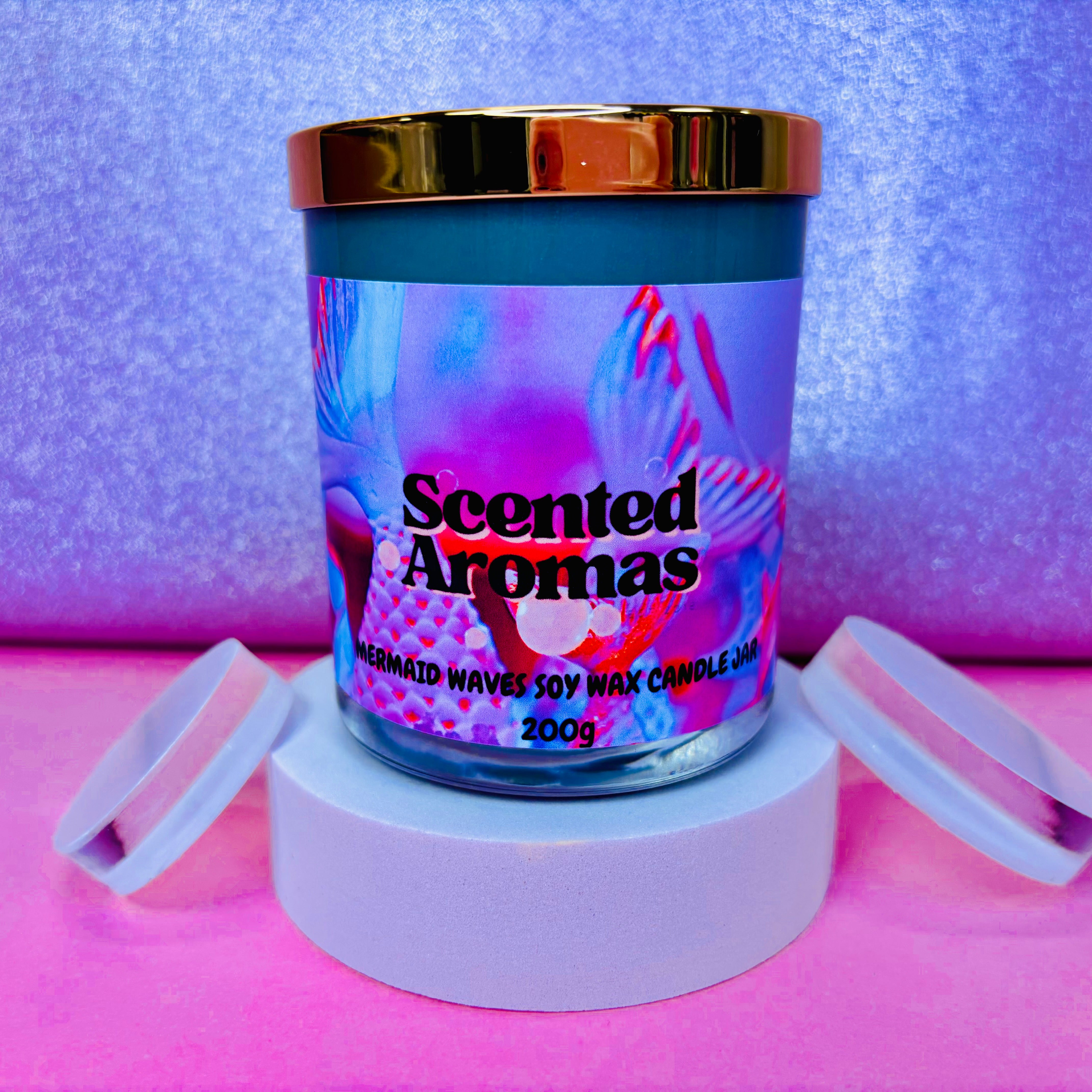 A vibrant Twisted Mermaid Candle by The Soap Gal x, weighing 200g, exudes luxury as it is displayed on a white stand against a lively pink and purple background.