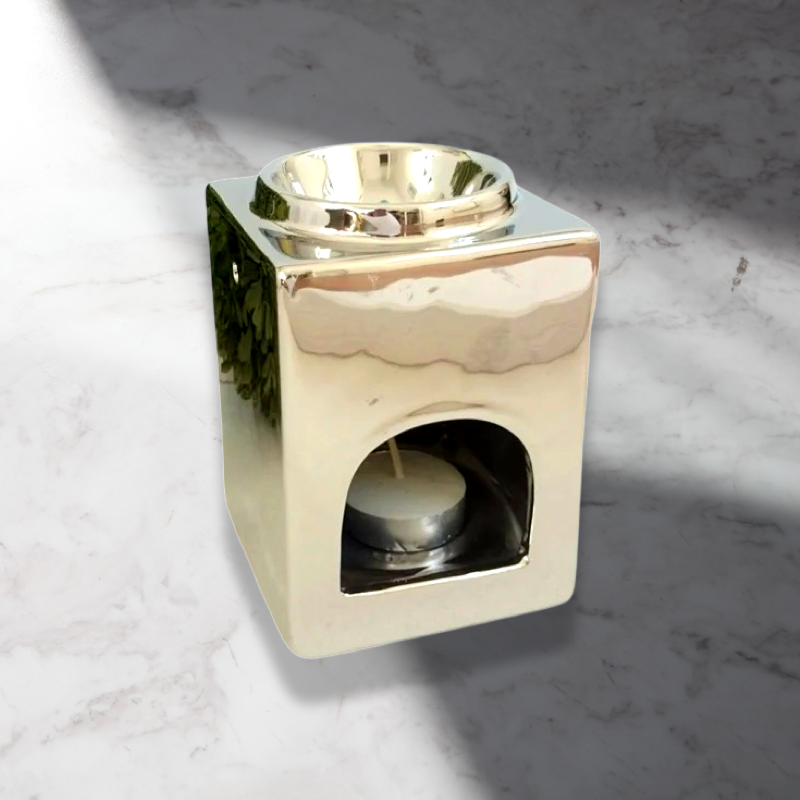 The Soap Gal x Square Ceramic Wax Melter in Silver is a shiny minimalist piece with a square design, featuring a bowl on top and space below for a tea light candle.