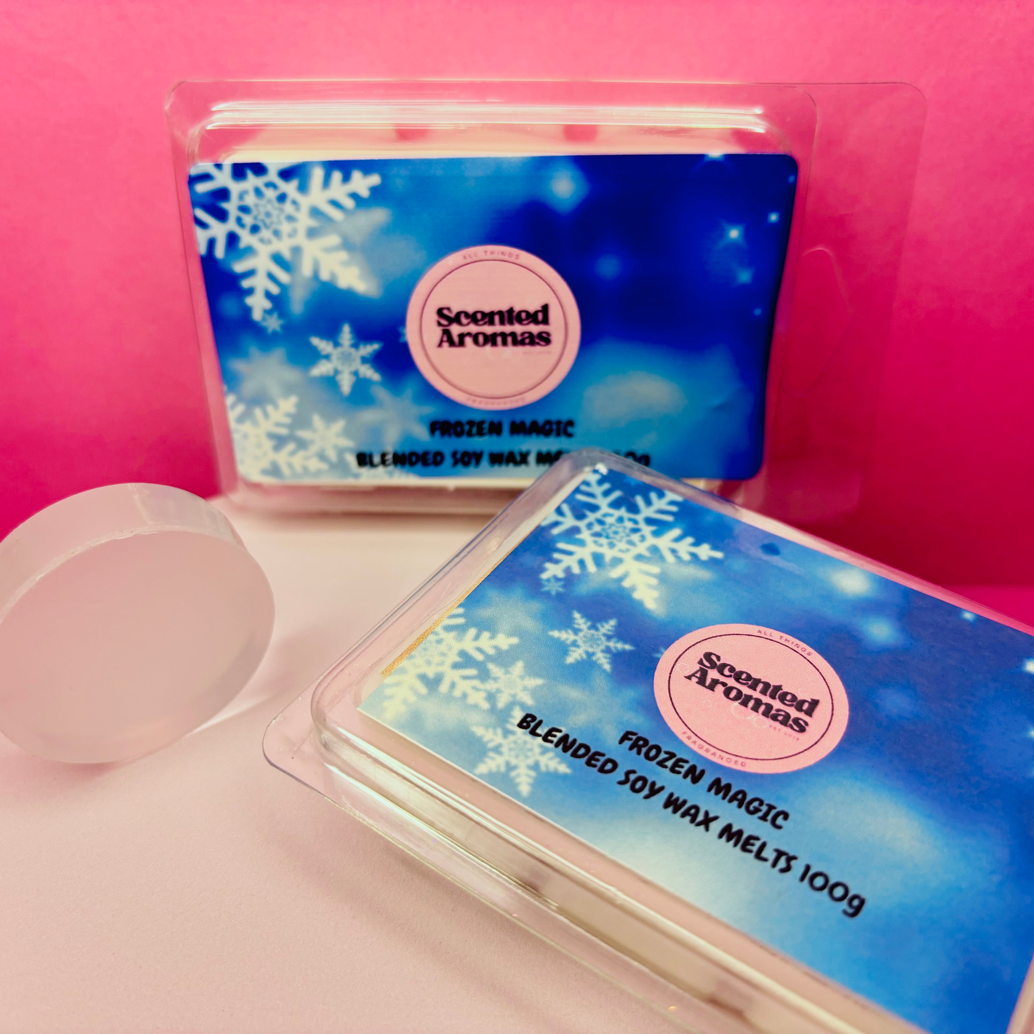 Two packs of "Frozen Magic Wax Melts 85g" by The Soap Gal x showcase a blue snowflake design on a pink background and provide a long-lasting scent throw.