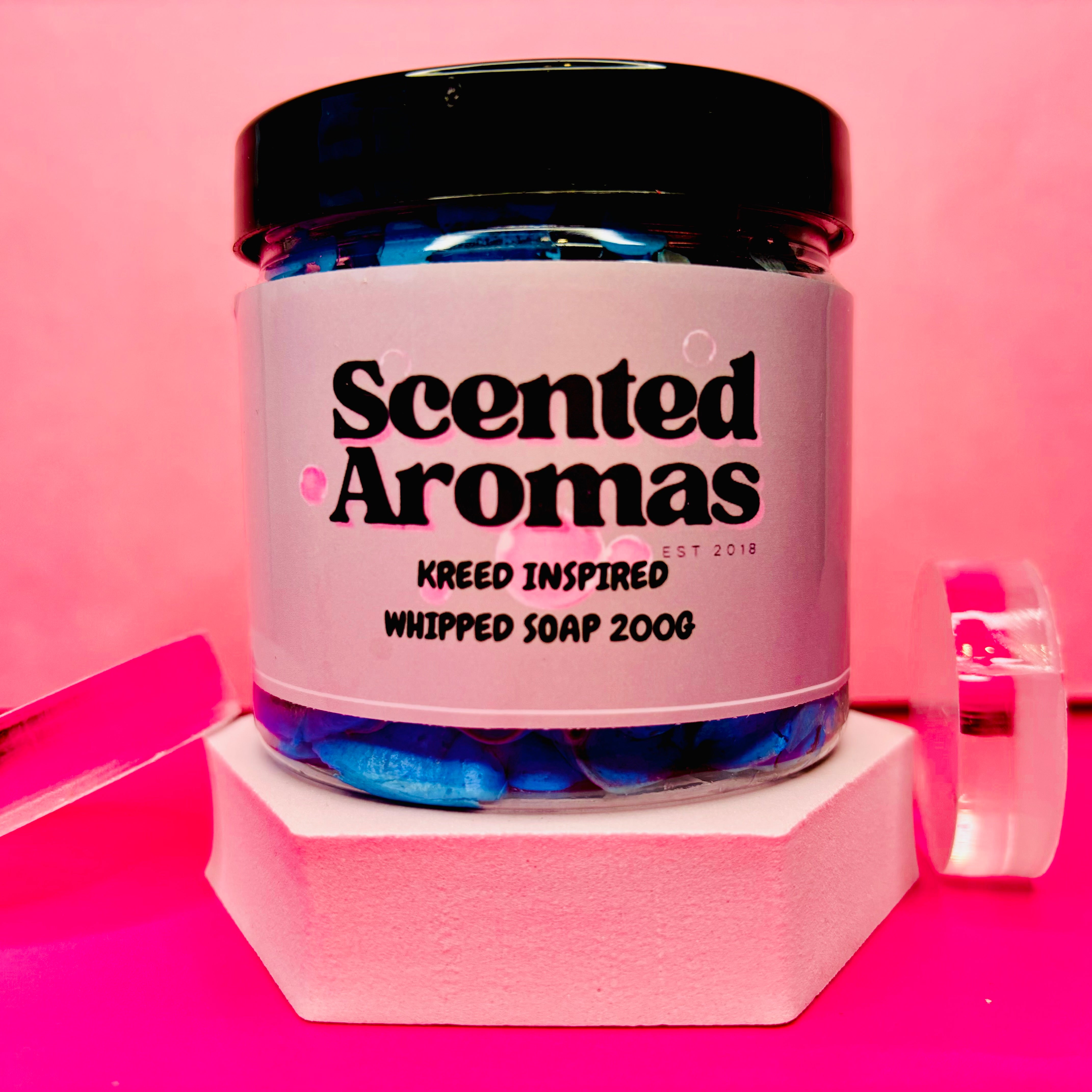 A jar of "The Soap Gal x Kreed Whipped Soap Shave Butter 200g," ideal for men's grooming needs, is set against a pink background.