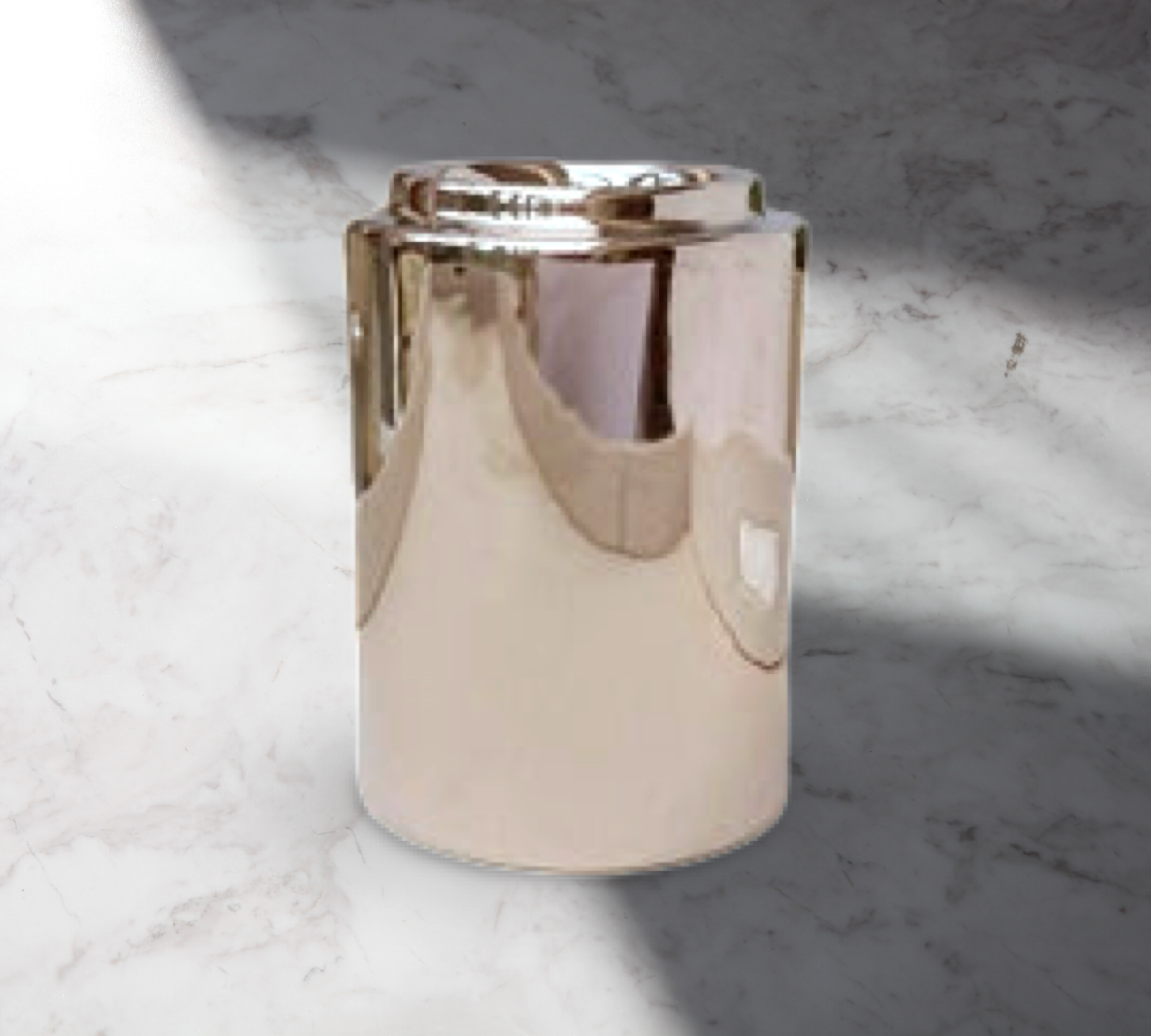 The Cylinder Ceramic Wax Melter - Silver by The Soap Gal x, with its reflective finish, stands on a marble floor, partially in shadow.