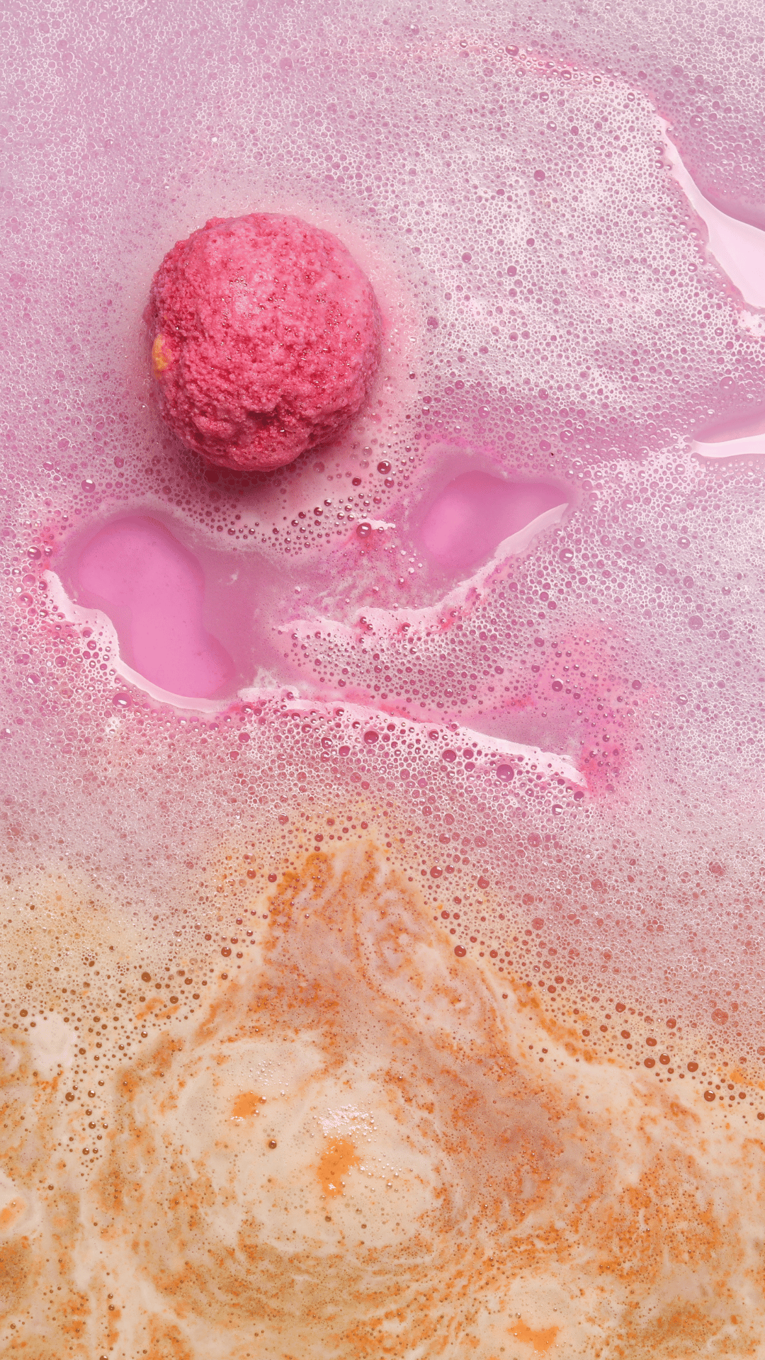 Three Rhubarb & Custard Cocoa Shea Butter Bath Bombs from Scented Aromas, adorned with creamy white frosting and red jelly-like tops, rest elegantly on a purple surface. Each one is sprinkled with Bio Glitter and small gold heart decorations, adding an extra touch of indulgence to your bath time.