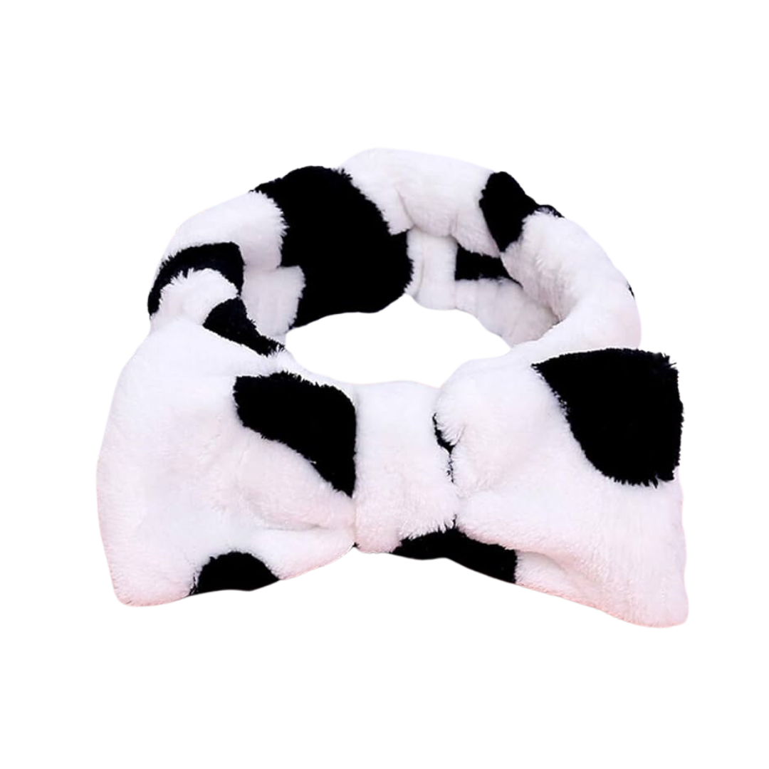 Infuse your routine with a hint of whimsy using The Soap Gal x's Shower Cow Print Headband. Featuring a playful bow, this self-care essential effortlessly enhances your style against a white backdrop.