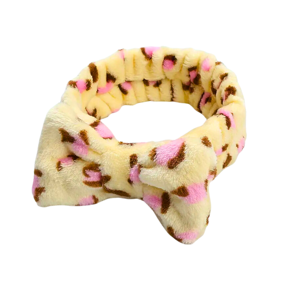 Indulge in the luxurious comfort of The Soap Gal x Shower Pink Leopard Print Headband, featuring a plush design with a charming pink and brown leopard print on a vibrant yellow background. This elegant headband, complete with a stylish bow, is perfect for adding a wild flair to your beauty routine.